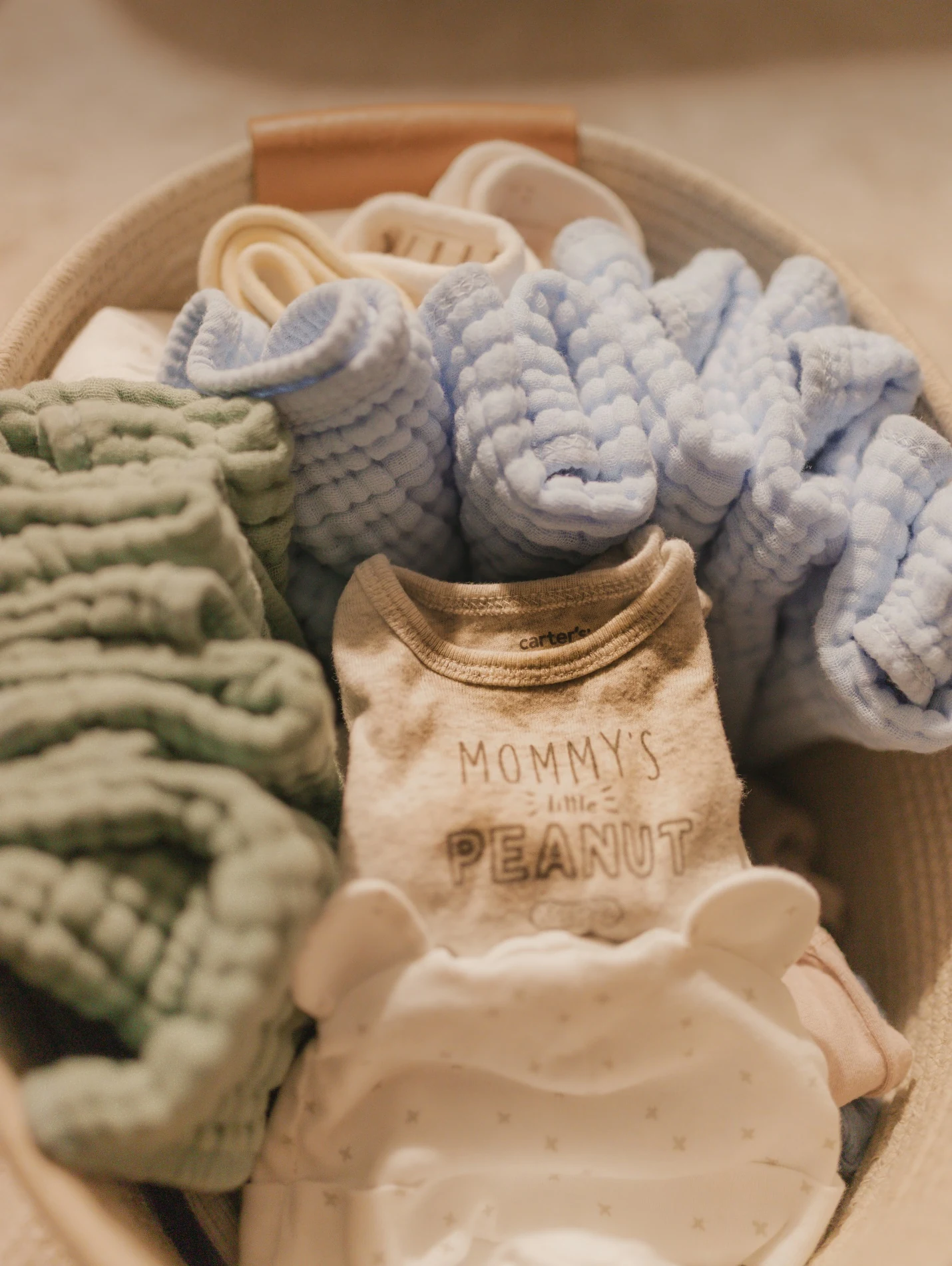 Baby clothes and newborn essentials arranged in a basket for a hospital bag