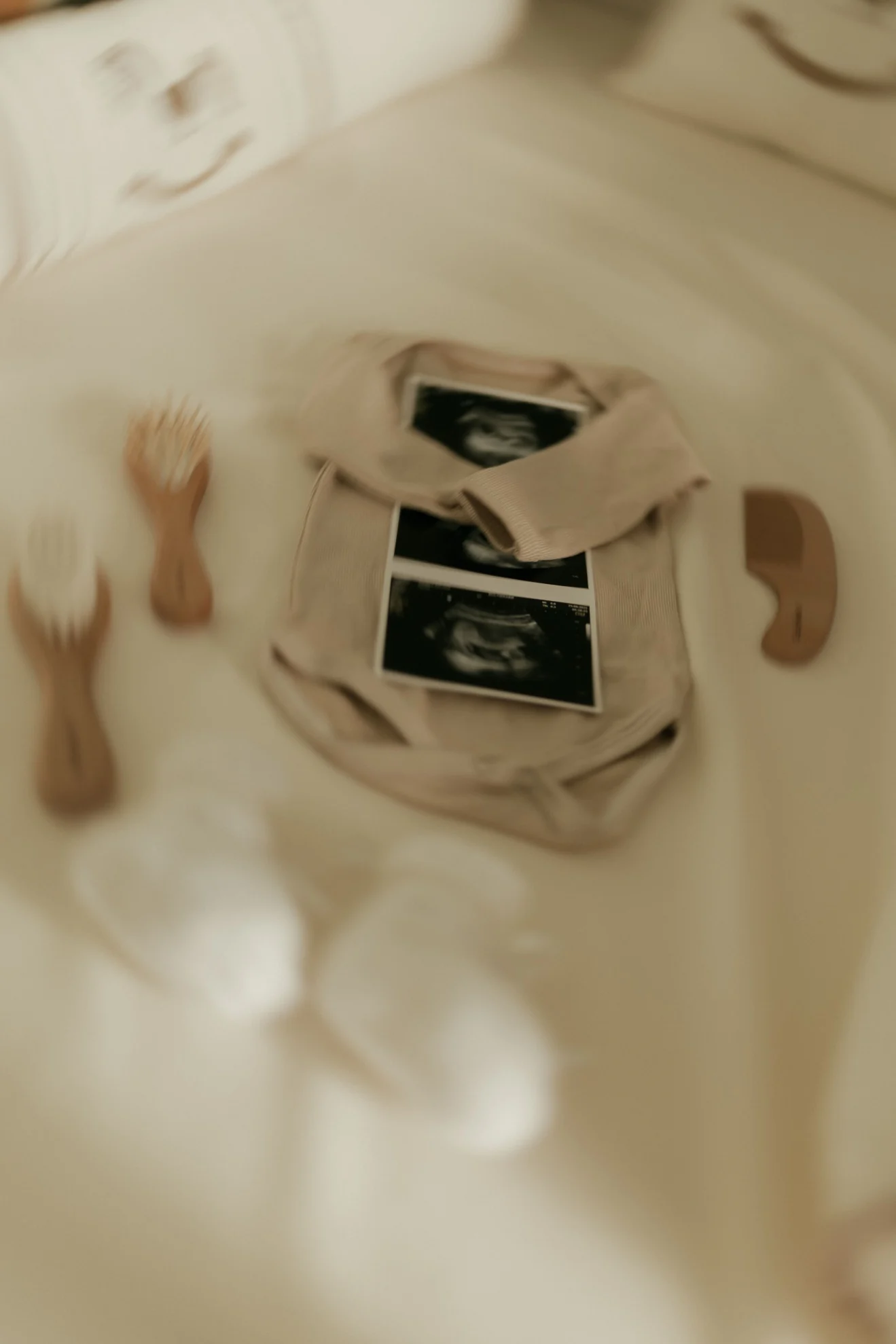 Ultrasound photographs with baby clothes laid out while preparing for delivery